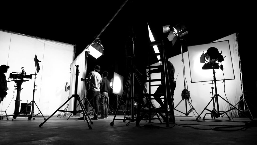 Filmstudio mit Scheinwerfern, Stativen und Filmcrew in Schwarzweiß