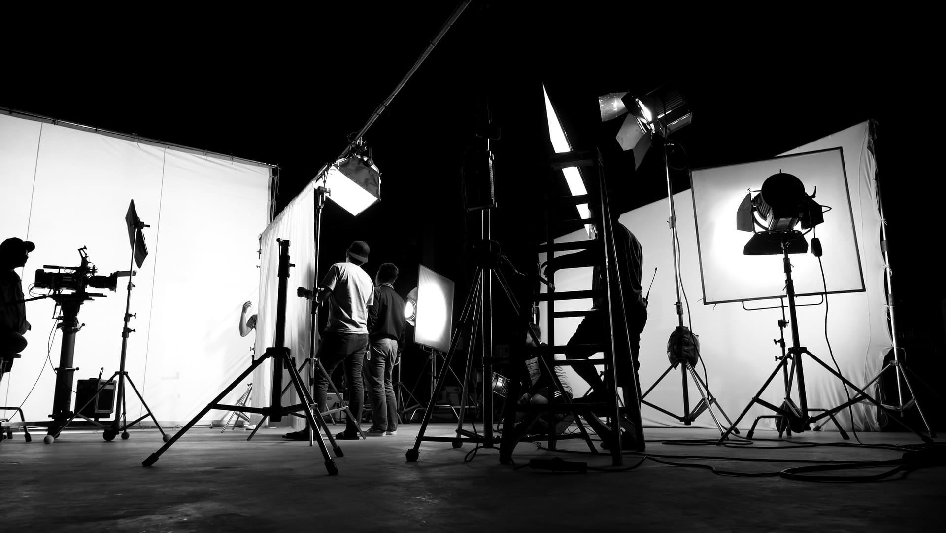 Filmstudio mit Scheinwerfern, Stativen und Filmcrew in Schwarzweiß